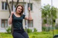 Young woman swinging on swing in the park with copy space. Freedom and happiness concept