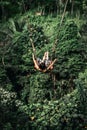 Young woman swings in the jungle of Bali island. Rainforest of Indonesia. Travel concept.