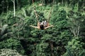 Young woman swings in the jungle of Bali island. Rainforest of Indonesia. Travel concept.