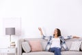 Young woman switching on air conditioner