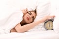 Young woman switching off alarm clock while lying in bed at home Royalty Free Stock Photo