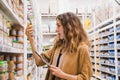 Young woman with a tablet in shock from the composition of baby food in a supermarket, the girl emotionally reads the Royalty Free Stock Photo