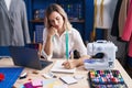 Young woman tailor drawing clothes on notebook at clothing factory