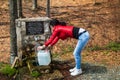 Young woman take a water on drinking fountain in a forest