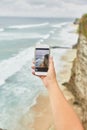 Young woman takes pictures on her phone. Girl taking pictures of a landscape. Royalty Free Stock Photo