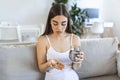 Young woman takes pill with glass of water in hand. Stressed female looking in window and drinking sedated antidepressant meds. Royalty Free Stock Photo