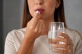 Young woman takes a pill while holding a glass of water in her hand Royalty Free Stock Photo