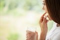 Young woman takes round pill with glass of water in hand Royalty Free Stock Photo