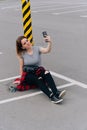A young woman takes a selfie with her longboard. Concept of summer hobby