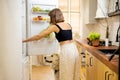 Woman with dog opens fridge filled with healthy food ingredients Royalty Free Stock Photo