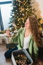 Young woman takes toys for the Christmas tree out of the box Royalty Free Stock Photo