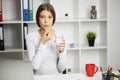 Young woman takes white round pill with glass of water in hand Royalty Free Stock Photo