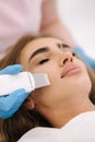 Young woman taking beauty procedure in spa salon. Beautician using peeling device, ultrasonic clining. Gorgeous woman Royalty Free Stock Photo