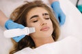 Young woman taking beauty procedure in spa salon. Beautician using peeling device, ultrasonic clining. Gorgeous woman Royalty Free Stock Photo