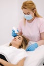 Young woman taking beauty procedure in spa salon. Beautician using peeling device, ultrasonic clining. Gorgeous woman Royalty Free Stock Photo