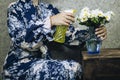 Young woman taking care of daisy flowers. Cheerful housewife in apron spraying hydrangea leaves with pesticide Royalty Free Stock Photo