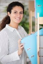 young woman taking folder with documents from shelf in archive Royalty Free Stock Photo