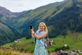 Young woman taking her smartphone in the alps. Royalty Free Stock Photo
