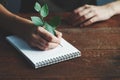 Young woman taking notes, writing with green plant as pen on notebook, eco lifestyle Royalty Free Stock Photo