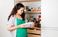 Young woman taking out dishware of the cupboard to set the table Royalty Free Stock Photo