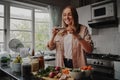 Young woman taking photo of her food with smart phone in modern kitchen at home during isolation and quarantine Royalty Free Stock Photo