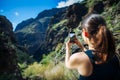 Young woman taking a photo with her phone of amazing mountains l