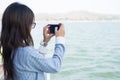 Young woman taking photo scenery while standing on boat. front o