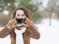 Young woman taking photo using cell phone in winter park Royalty Free Stock Photo