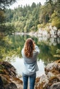 Young woman taking photos of beautiful scenery lake mountains with smartphone. Sustainable travel concept