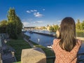 Young woman, taking picture with her cell phone from Legion Bridge with view on Kampa island, Vltava river, Prague Castle, Old Tow