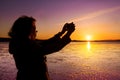 Young woman taking picture of herself, selfie, on a beach during sunset. Royalty Free Stock Photo