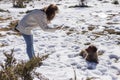 Young woman taking a picture with mobile phone to he brown dog sitting on the snow and wearing red ski goggles Royalty Free Stock Photo