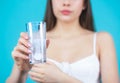 Young woman taking pill against headache. Brunette taking a pill with a glass of water. Woman taking drugs to releave Royalty Free Stock Photo
