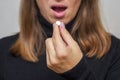 Young woman taking a pill. A woman takes medicine antidepressant or birth control pill, female puts tablet in mouth have