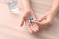 Young woman taking pills at table, focus on hands Royalty Free Stock Photo