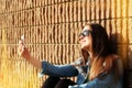 Young woman taking selfie in front of a brick wall