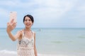 Young woman taking selfie by mobile phone in beach Royalty Free Stock Photo