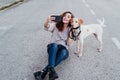 young woman taking a selfie with mobile phone with her dog at the street. autumn season Royalty Free Stock Photo