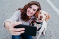 young woman taking a selfie with mobile phone with her dog at the street. autumn season Royalty Free Stock Photo