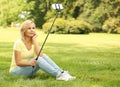 Young woman taking selfie photo with stick in park Royalty Free Stock Photo