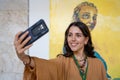 Young woman taking selfie photos with paintings in the art gallery.