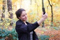 Young woman taking selfie with smartphone in forest Royalty Free Stock Photo