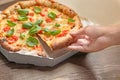 Young woman taking slice of delicious pizza Margherita from carton box on table Royalty Free Stock Photo