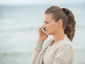 Young woman talking cell phone on cold beach Royalty Free Stock Photo