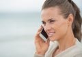 Young woman talking cell phone on cold beach Royalty Free Stock Photo