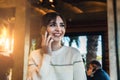 Young woman talking on cell phone while sitting alone in coffee shop.Smiling girl has telephone conversation while resting in cafe Royalty Free Stock Photo