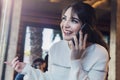 Young woman talking on cell phone while sitting alone in coffee shop.Smiling girl has telephone conversation while resting in cafe Royalty Free Stock Photo