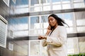 Young woman talking on cellphone and looking at wristwatch outdoors Royalty Free Stock Photo