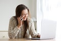 Young woman talking on mobile phone and looking at laptop computer Royalty Free Stock Photo