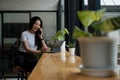 Young woman talking on mobile phone and writing notes on digital tablet while sitting at her desk. Asian female working Royalty Free Stock Photo